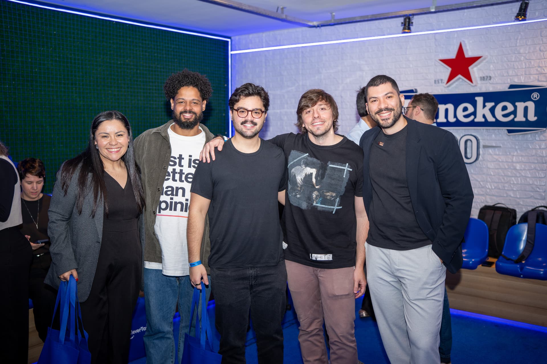 Grupo de convidados do SHIFT em frente ao painel do patrocinador
